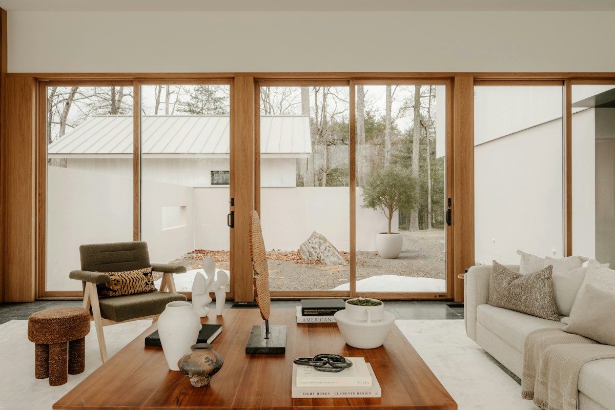 Warm residential living room with wood-framed windows overlooking a courtyard